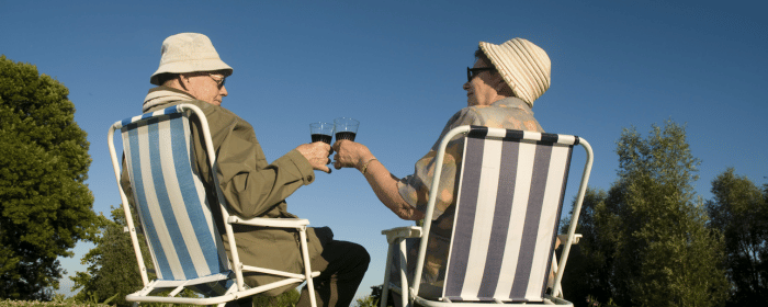 Two seniors enjoying drinks outdoors, symbolizing relaxation and security. Stay safe with a reliable Texas medical alert system.